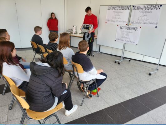 Mitarbeiter einer Firma besucht die Mittelschule und erklärt Schülern etwas über Technik