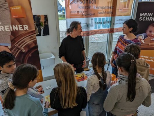 Schüler stehen vor einem Stand an dem eine Firma sich vorstellt