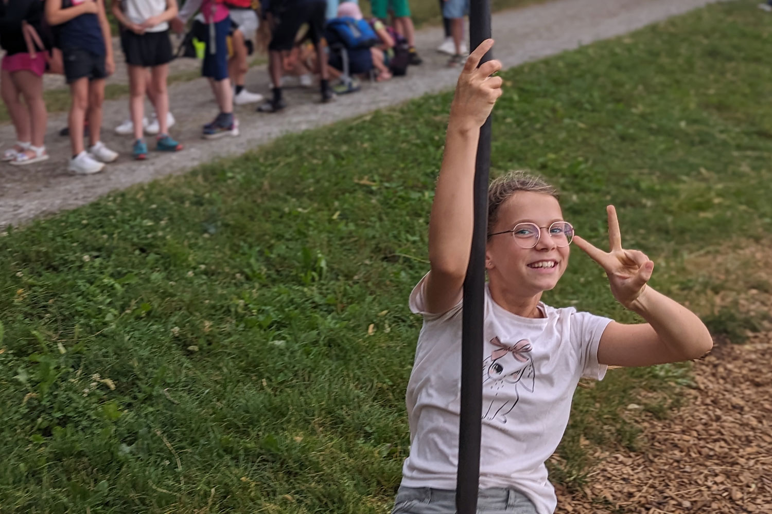 Schülerin auf einer Seilbahn zeigt das Peace-Zeichen