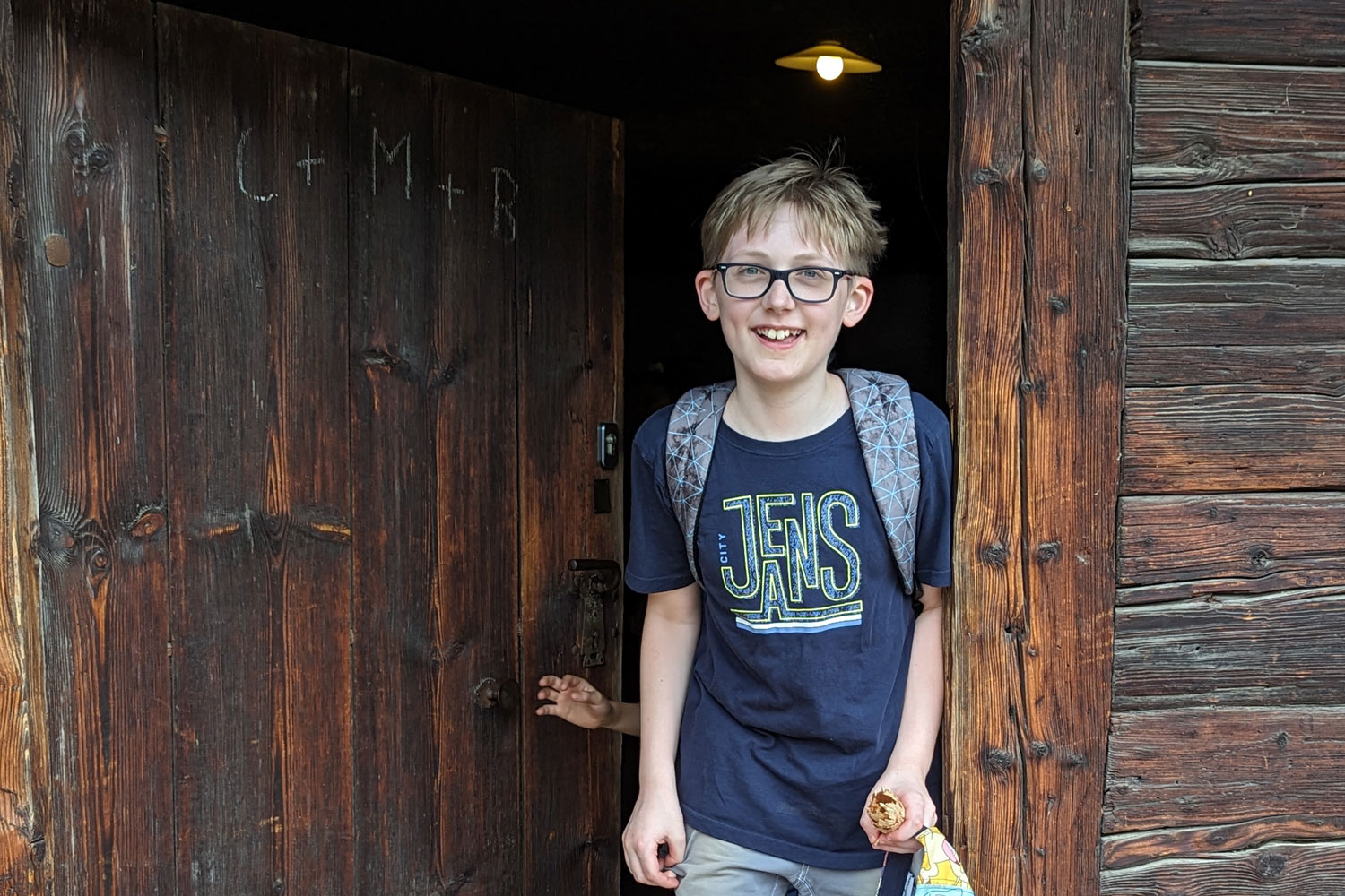 Schüler geht aus einer Holztür raus und lächelt
