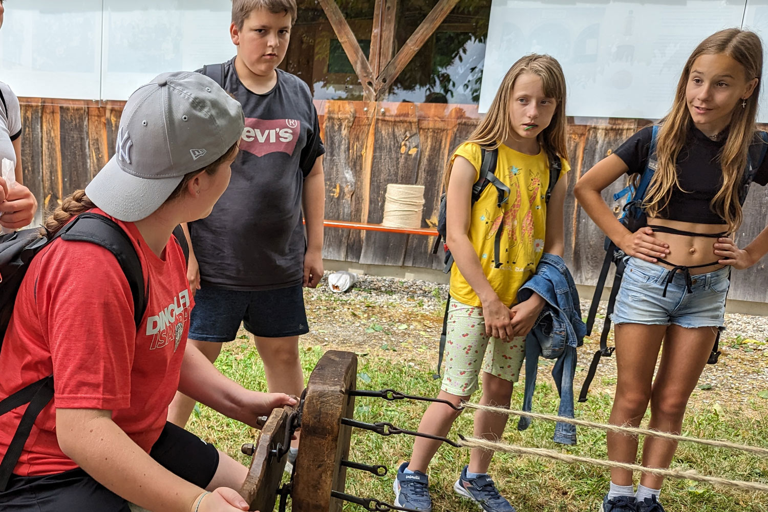 Schüler stehen vor einem Gerät aus Holz mit Seilen