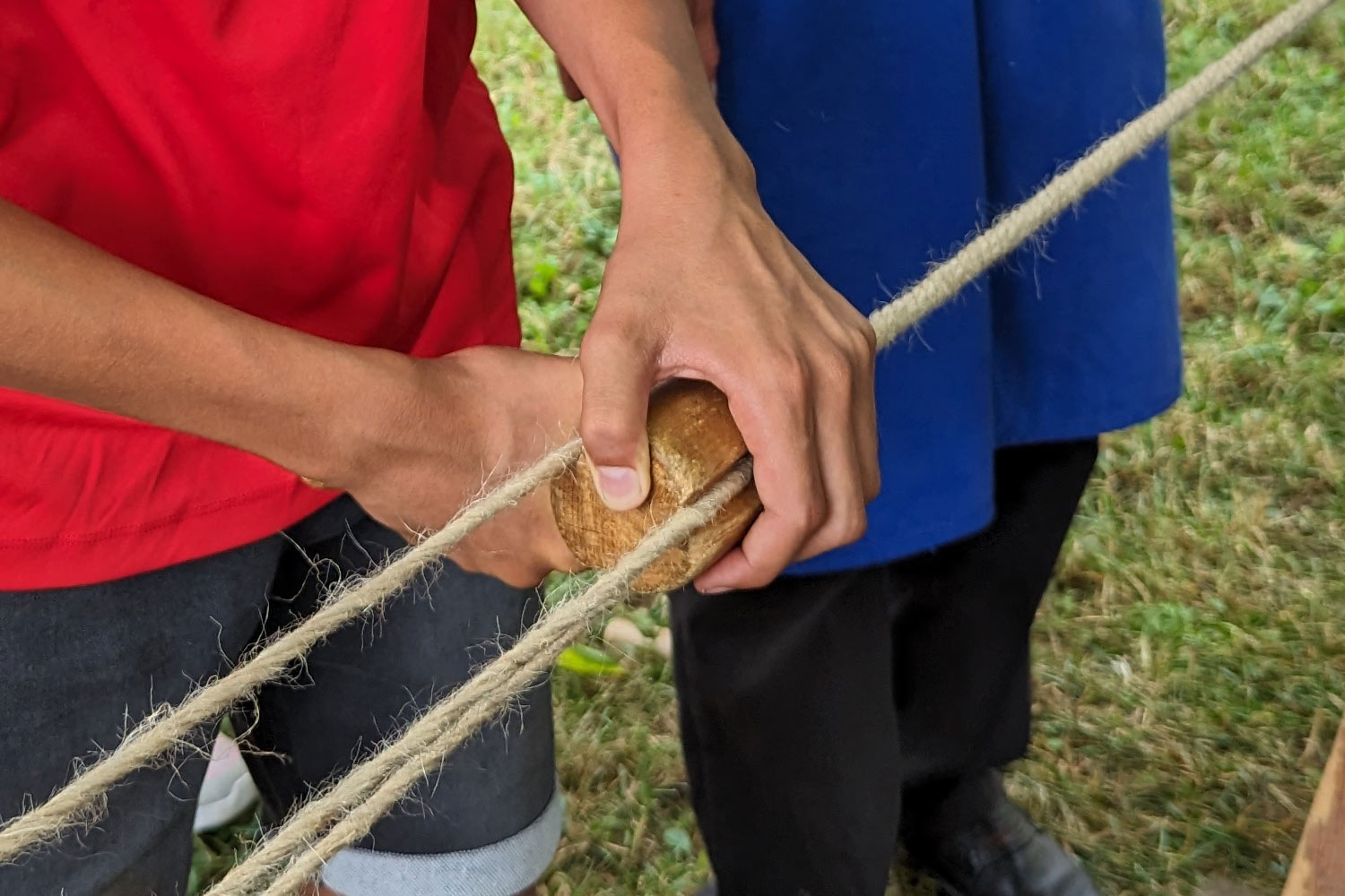 Ein Schüler hält ein Holzstück an eine Schnur, eine weitere Person steht daneben