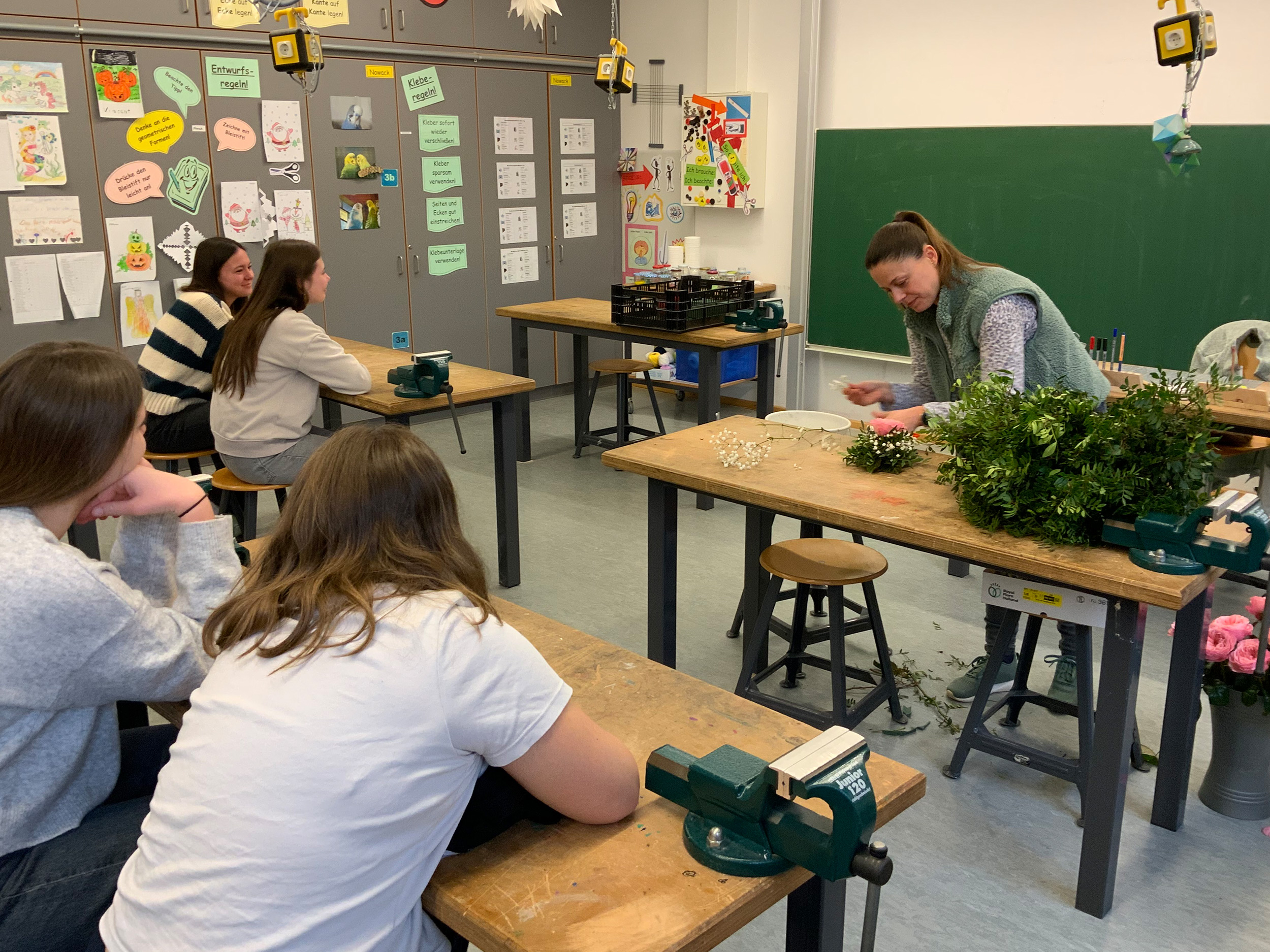Schülerinnen und Schüler beim Herstellen von Tischgestecken mit Blumen.