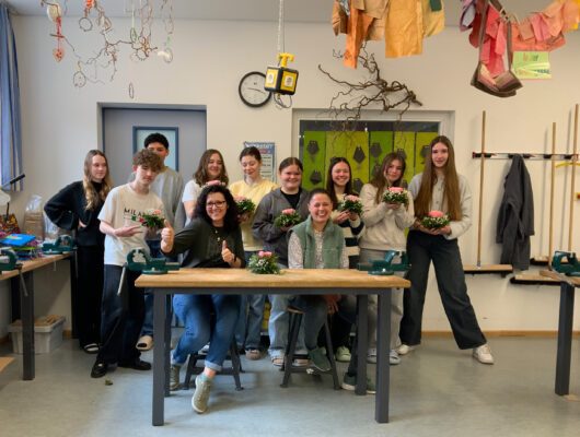 Schülerinnen und Schüler beim Herstellen von Tischgestecken mit Blumen.